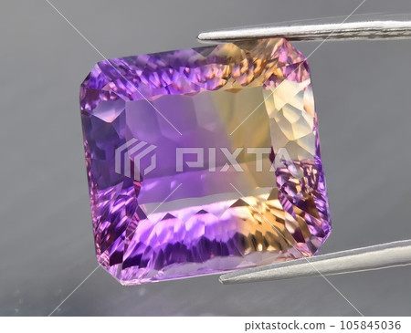 Natural gemstone yellow purple ametrine on a gray background. Purple variety of quartz Natural gemstone yellow purple ametrine on a gray background. Purple variety of quartz 105845036
