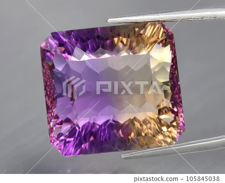 Natural gemstone yellow purple ametrine on a gray background. Purple variety of quartz Natural gemstone yellow purple ametrine on a gray background. Purple variety of quartz 105845038