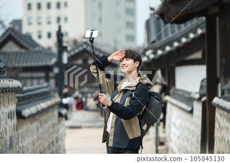 A young man traveling around a traditional village and taking pictures with a smartphone camera A young man traveling around a traditional village and taking pictures with a smartphone camera 105845130