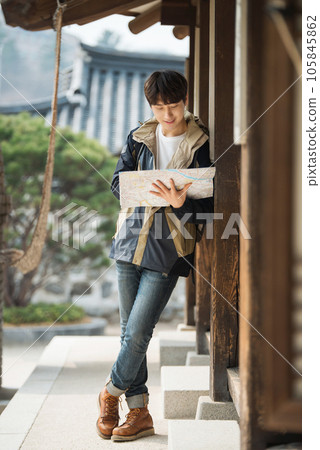 A young male college student who travels with a backpack looking at a map in Korea 105845862