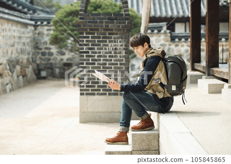 A young male college student who travels with a backpack looking at a map in Korea 105845865