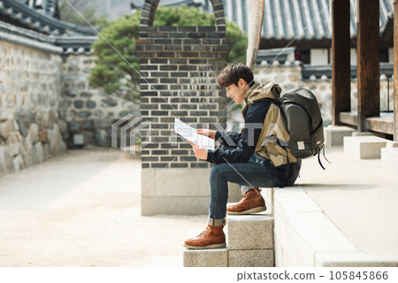 A young male college student who travels with a backpack looking at a map in Korea 105845866