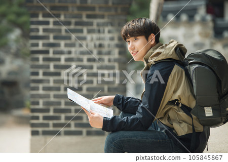A young male college student who travels with a backpack looking at a map in Korea 105845867