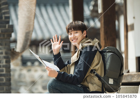 A young male college student who travels with a backpack looking at a map in Korea A young male college student who travels with a backpack looking at a map in Korea 105845870