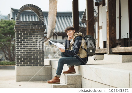 A young male college student who travels with a backpack looking at a map in Korea A young male college student who travels with a backpack looking at a map in Korea 105845871