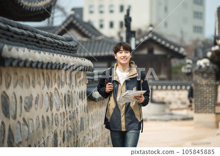 A young male college student who travels with a backpack looking at a map in Korea A young male college student who travels with a backpack looking at a map in Korea 105845885