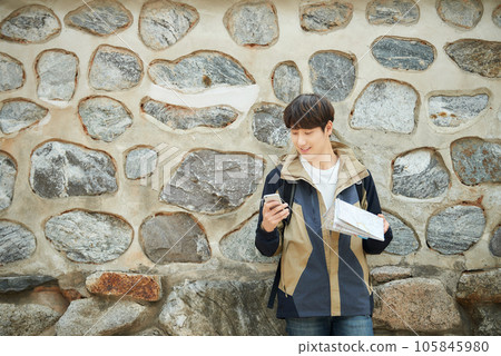 A young male college student looking at a map and searching on his smartphone while traveling to Korea 105845980