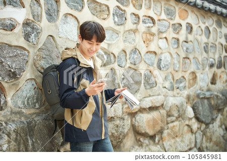 A young male college student looking at a map and searching on his smartphone while traveling to Korea 105845981