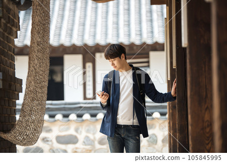 A young male college student looking at his smartphone while traveling to Korea 105845995