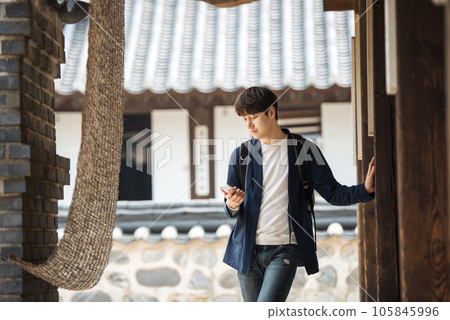 A young male college student looking at his smartphone while traveling to Korea A young male college student looking at his smartphone while traveling to Korea 105845996