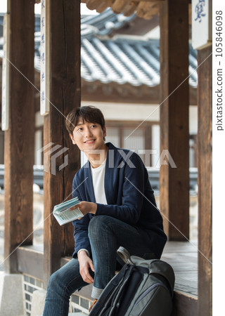 A young male college student sitting and looking at his passport during a trip to Korea 105846098