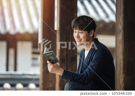 A young male college student sitting and looking at his passport during a trip to Korea 105846100
