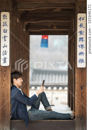 A young male college student sitting and looking at a tablet while traveling in Korea 105846171