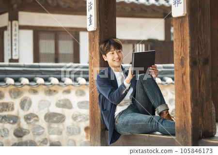 A young male college student sitting and looking at a tablet while traveling in Korea 105846173