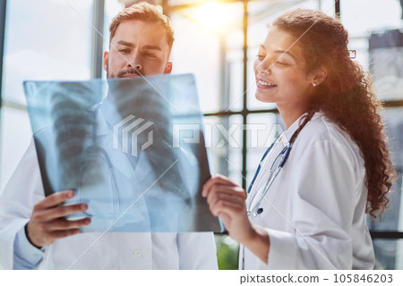 Young serious competent male doctor looking at X-ray at doctor's office 105846203