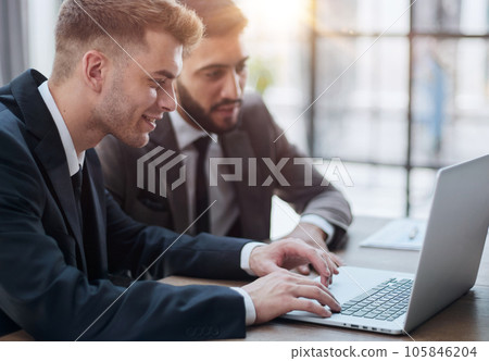two professional businessmen discussing and using desktop computer in office two professional businessmen discussing and using desktop computer in office 105846204