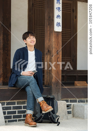 A young man sitting on the stairs looking at his smartphone 105847208