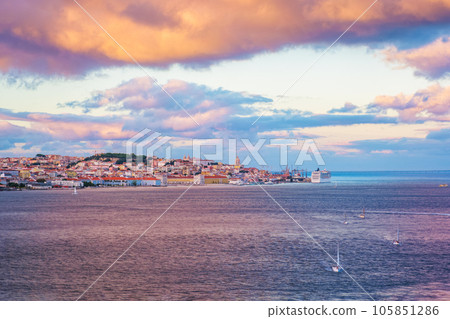 View of Lisbon over Tagus river from Almada with yachts tourist boats and moored cruise liner on sunset with dramatic sky. Lisbon, Portugal View of Lisbon over Tagus river from Almada with yachts tourist boats and moored cruise liner on sunset with dramatic sky. Lisbon, Portugal 105851286