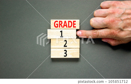 Time to grade 1 symbol. Concept word Grade 1 2 3 on wooden block. Businessman hand. Beautiful grey table grey background. Business planning and time to grade 1 concept. Copy space. 105851712