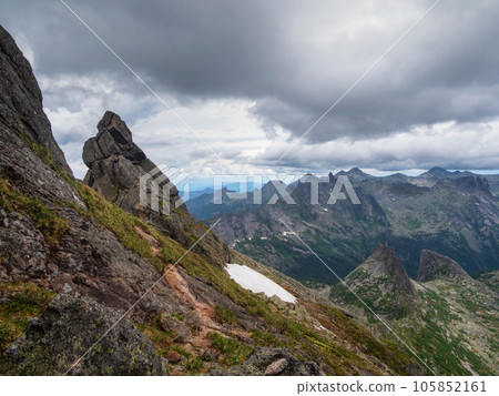 Pointed cliffs mountainside. Ghost rocks. Awesome scenic mountain landscape with big cracked pointed stones in misty rainy morning. Sharp rocks background. 105852161