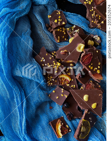 Pieces of homemade chocolate with hazelnuts and nuts on a black background 105852674
