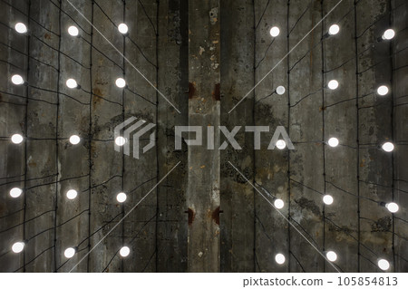Turned-on white tone light bulbs in lamps lined up under grey painted cement ceiling - rustic and loft style - open space - perspective worm view 105854813
