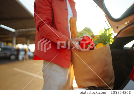 Young man with shopping bag full of vegetables near the car. Handsome man after shopping. Young man with shopping bag full of vegetables near the car. Handsome man after shopping. 105854868