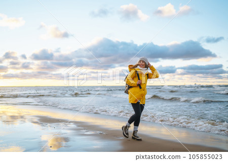 Happy tourist in a yellow jacket enjoying sea landscape at sunset. Travelling, lifestyle, adventure. Happy tourist in a yellow jacket enjoying sea landscape at sunset. Travelling, lifestyle, adventure. 105855023