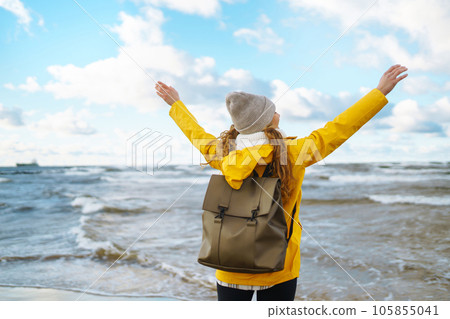 Happy tourist in a yellow jacket enjoying sea landscape at sunset. Travelling, lifestyle, adventure. 105855041