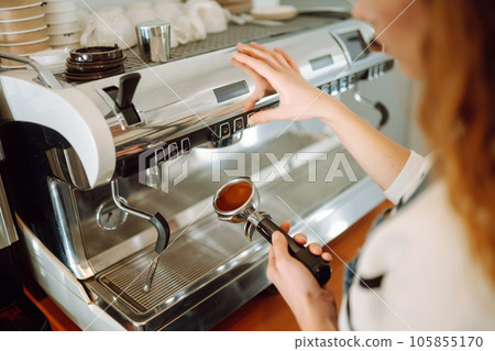 Female barista making coffee in a coffee machine. Conception of business and service. Takeaway food. Female barista making coffee in a coffee machine. Conception of business and service. Takeaway food. 105855170
