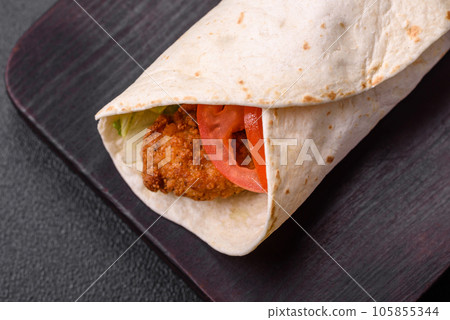 Delicious roll with chicken nuggets, tomatoes, lettuce and sauces with salt and spices 105855344