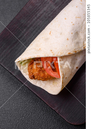 Delicious roll with chicken nuggets, tomatoes, lettuce and sauces with salt and spices 105855345