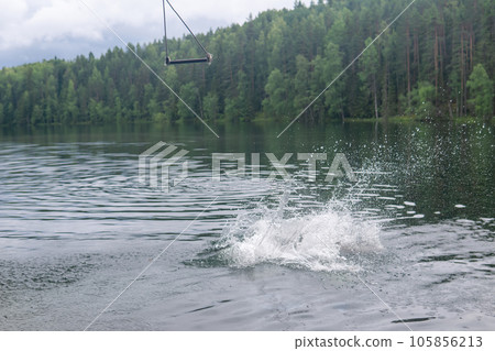 splash on the water - a bather dived into a forest lake from a makeshift tarzan swing 105856213