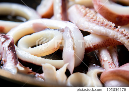 A close-up of a cooking scene in which squid (boiled squid) is fried in a frying pan. 105856376