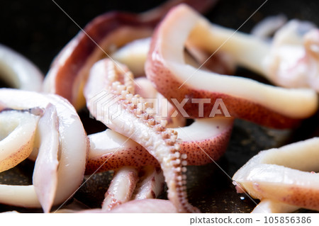 煎鍋裡煎魷魚(煮魷魚)的烹飪場景特寫。 煎鍋裡煎魷魚(煮魷魚)的烹飪場景特寫。 105856386