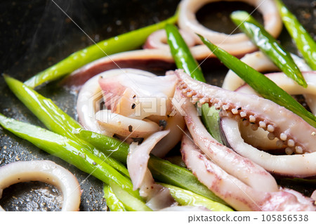 A cooking scene where squid (boiled squid) and garlic sprouts are fried in a frying pan. A cooking scene where squid (boiled squid) and garlic sprouts are fried in a frying pan. 105856538