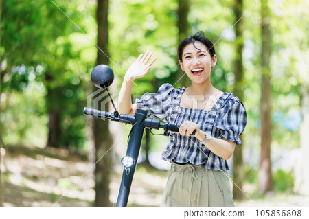 A young woman riding an electric kickboard on a tree-lined street A young woman riding an electric kickboard on a tree-lined street 105856808