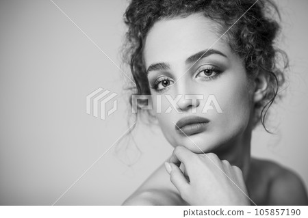 Black and white beauty portrait of attractive beautiful woman fashion model with collected dark curly hair and makeup, looking at camera. Indoor studio shot isolated on gray background. 105857190