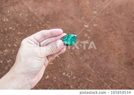 hand holding a small piece of emerald hand holding a small piece of emerald 105858534