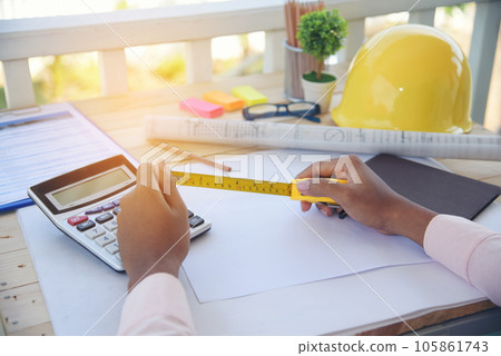 close up construction engineer man hands working at office desk architect workplace. Engineer Men hands drawing holding folder, use smartphone on office table drawing document blueprint hard hat close up construction engineer man hands working at office desk architect workplace. Engineer Men hands drawing holding folder, use smartphone on office table drawing document blueprint hard hat 105861743