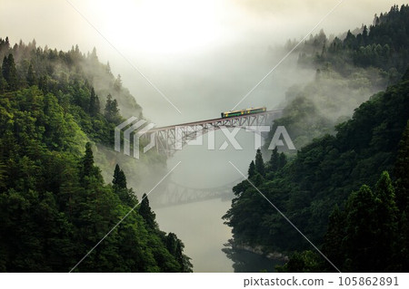 夏季，只見線紀波E120系列列車穿過第一隻見川大橋，晨霧籠罩（福島縣三島町，7月下旬） 105862891