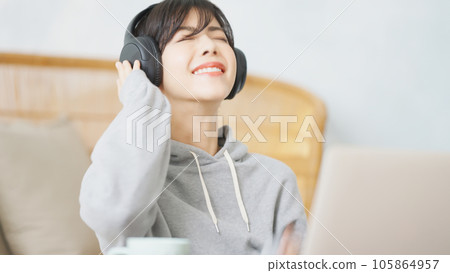 A woman working on a computer while listening to music with headphones 105864957