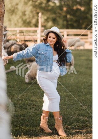 Stylish pregnant woman in a white hat in the countryside Stylish pregnant woman in a white hat in the countryside 105865710
