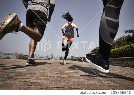 three young asian adults running jogging outdoors, rear and low angle view 105866848