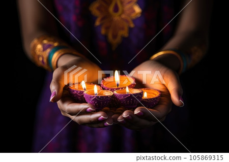 Woman hands with henna holding colorful clay diya lamps lit during diwali celebration Woman hands with henna holding colorful clay diya lamps lit during diwali celebration 105869315
