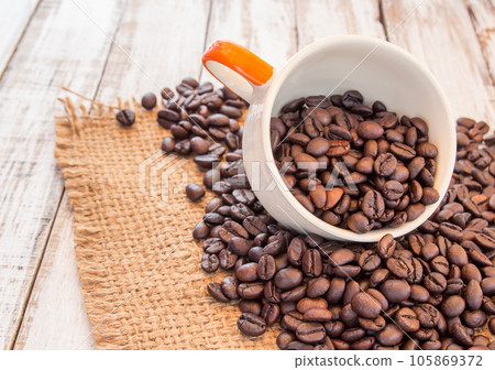 Coffee beans and coffee cup on wooden background Coffee beans and coffee cup on wooden background 105869372