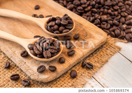 Coffee beans in wooden spoon on wooden background Coffee beans in wooden spoon on wooden background 105869374