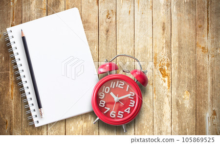 Red alarm clock and note book on brown wooden 105869525