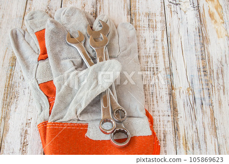 Leather work gloves and wrench on wooden table 105869623