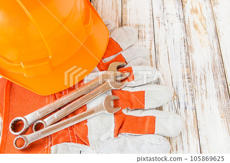 Leather work gloves and safety hat with wrench on wooden table Leather work gloves and safety hat with wrench on wooden table 105869625